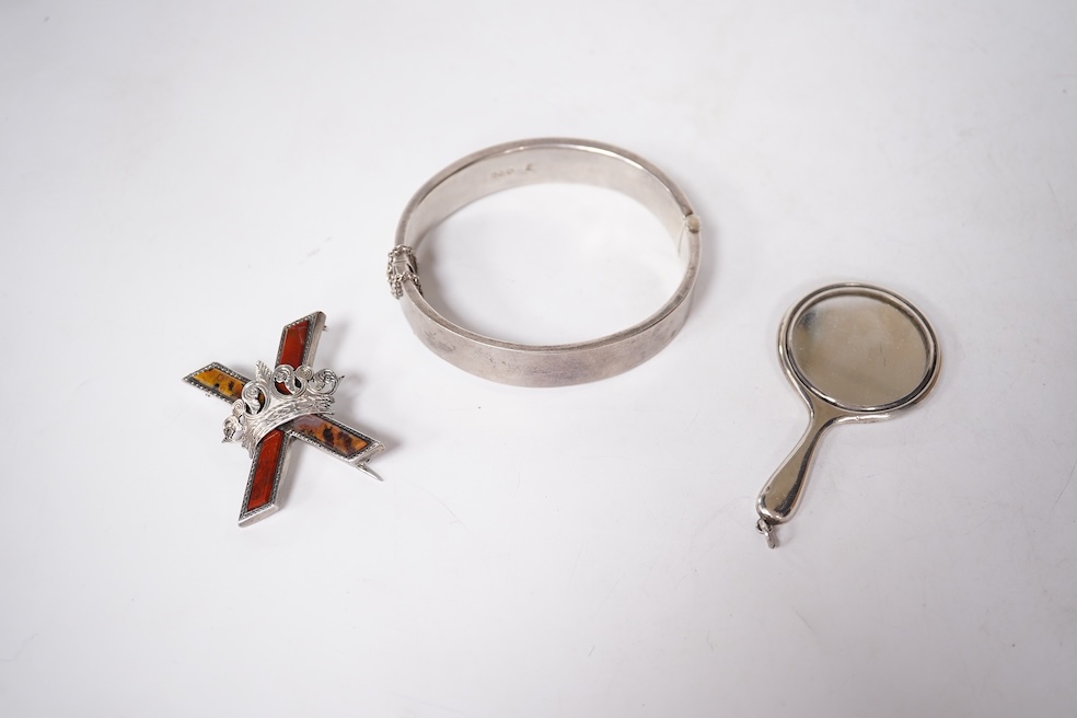 A late Victorian white metal and Scottish hardstone set 'X' brooch with coronet, 34mm, together with a silver hinged bangle and a George V silver mounted handbag mirror, with Reynold's Angels decoration. Condition - poor